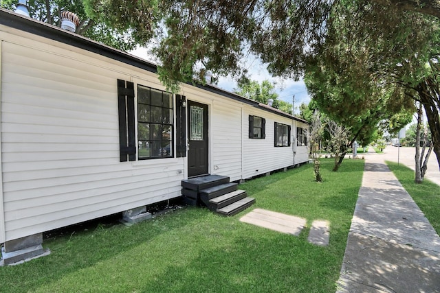 view of home's exterior with entry steps and a lawn