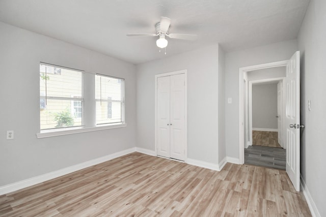 unfurnished bedroom with a ceiling fan, a closet, light wood-style flooring, and baseboards