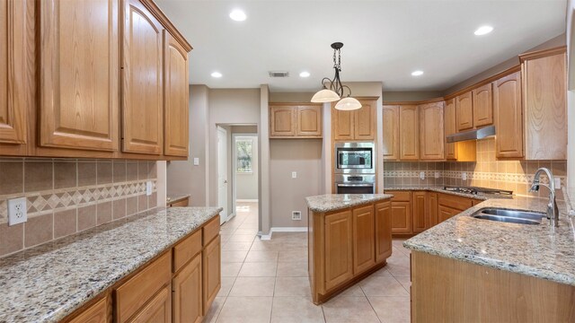 kitchen featuring backsplash, appliances with stainless steel finishes, a center island, sink, and light stone counters