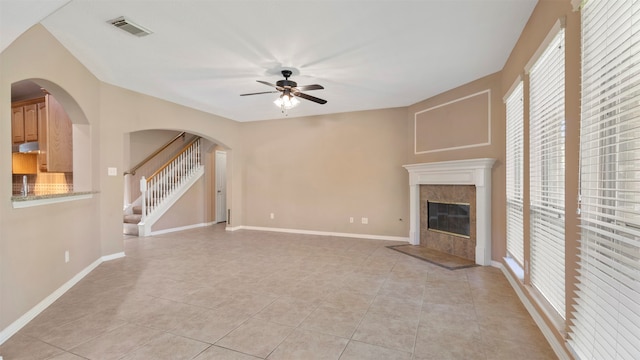 unfurnished living room featuring ceiling fan, light tile patterned flooring, and a fireplace