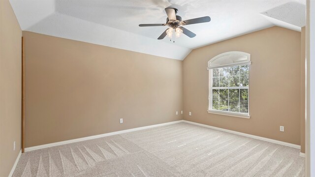 spare room with lofted ceiling, ceiling fan, and light carpet