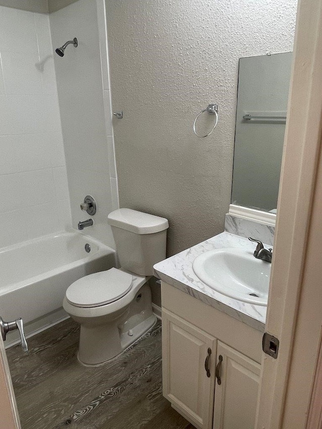 full bathroom with vanity, toilet, hardwood / wood-style floors, and washtub / shower combination