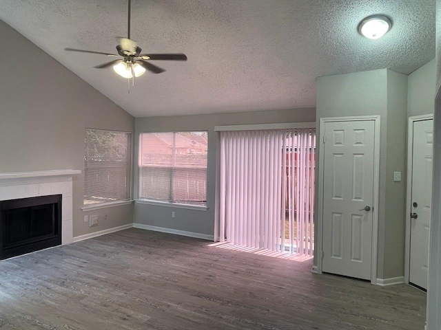 unfurnished living room with a tile fireplace, lofted ceiling, dark hardwood / wood-style floors, ceiling fan, and a textured ceiling