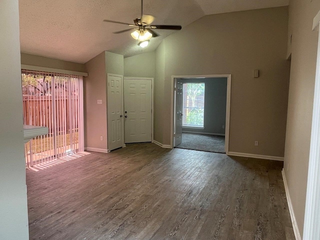 empty room with vaulted ceiling, dark hardwood / wood-style flooring, ceiling fan, and a textured ceiling