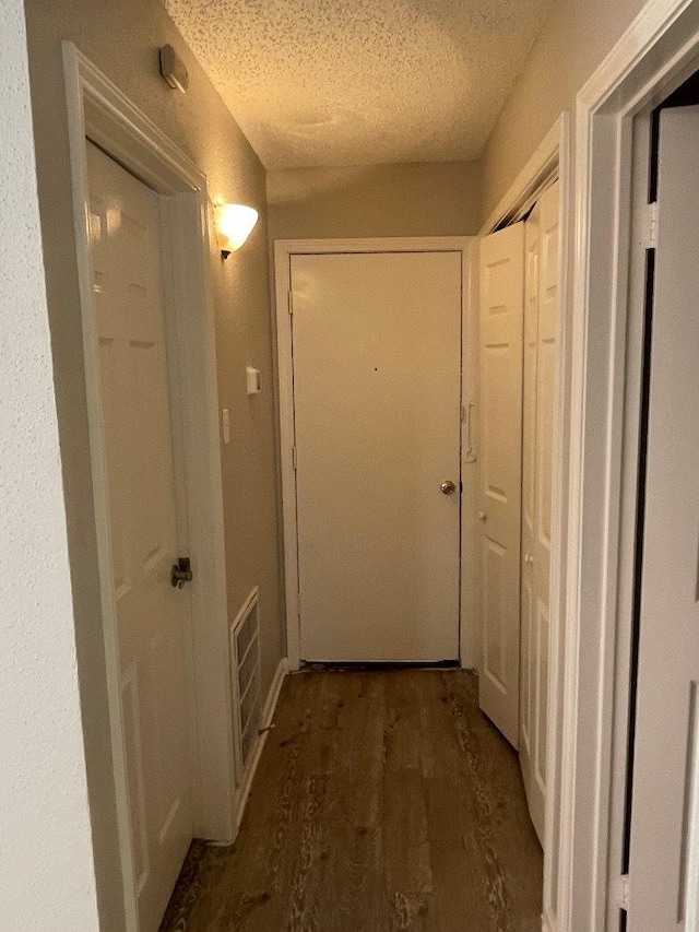 corridor with dark hardwood / wood-style flooring and a textured ceiling