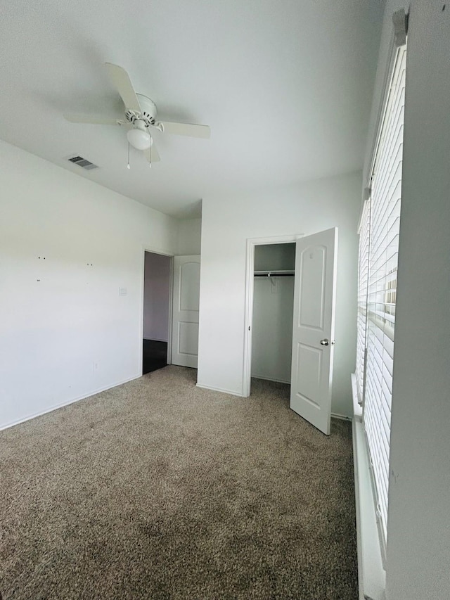 unfurnished bedroom with a closet, visible vents, a ceiling fan, and carpet