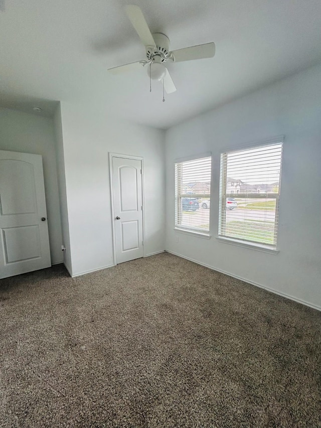 empty room featuring baseboards, carpet floors, and ceiling fan