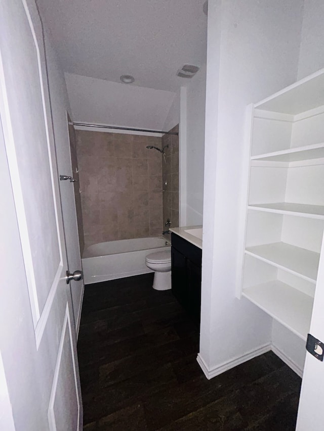 full bathroom with a textured ceiling, vanity, hardwood / wood-style floors, toilet, and tiled shower / bath combo