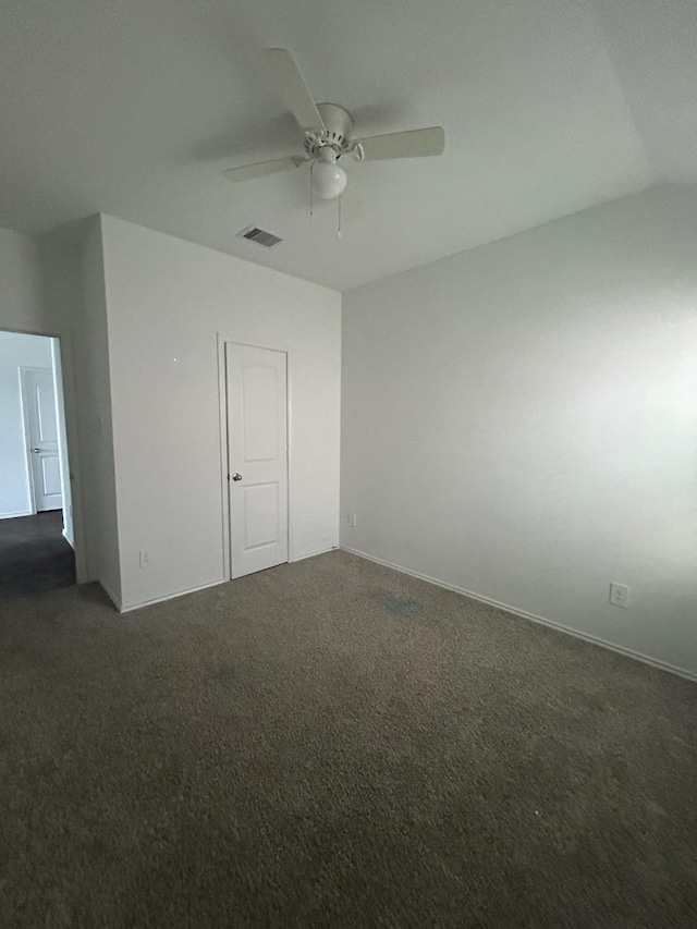 unfurnished room featuring dark colored carpet, visible vents, and a ceiling fan