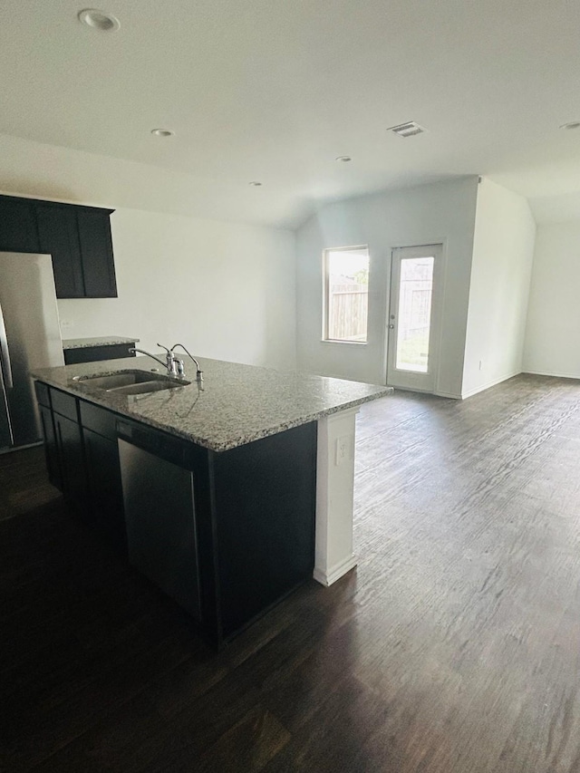 kitchen featuring visible vents, dark cabinets, an island with sink, dark wood-style flooring, and a sink