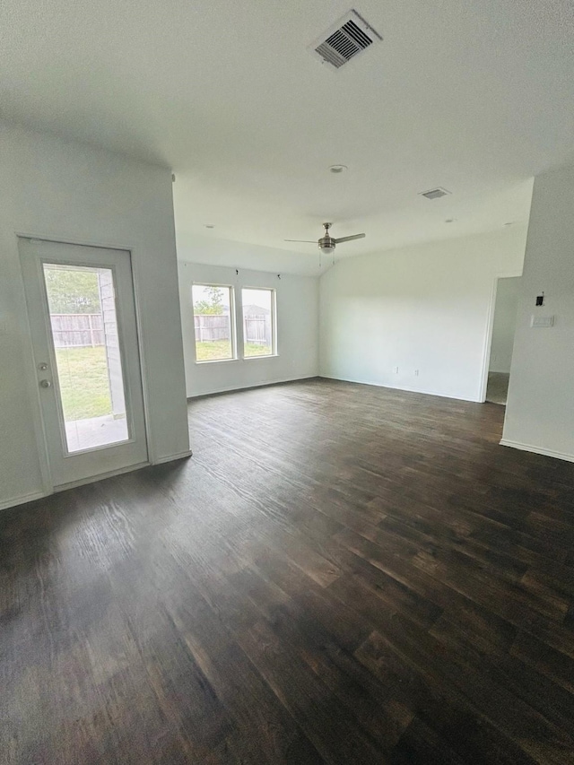 spare room featuring visible vents, baseboards, ceiling fan, and dark wood-style flooring