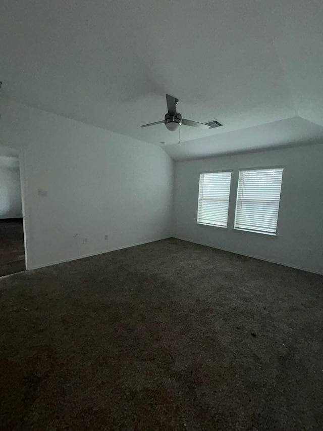 carpeted empty room featuring vaulted ceiling, a ceiling fan, and visible vents