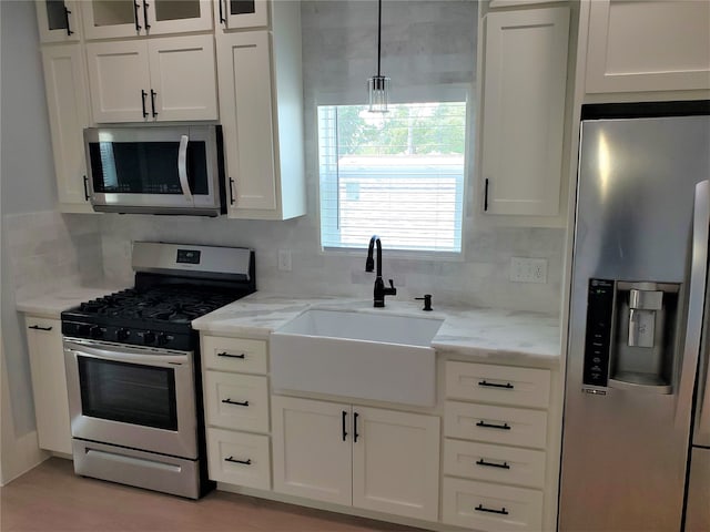 kitchen featuring white cabinets, appliances with stainless steel finishes, decorative backsplash, and sink