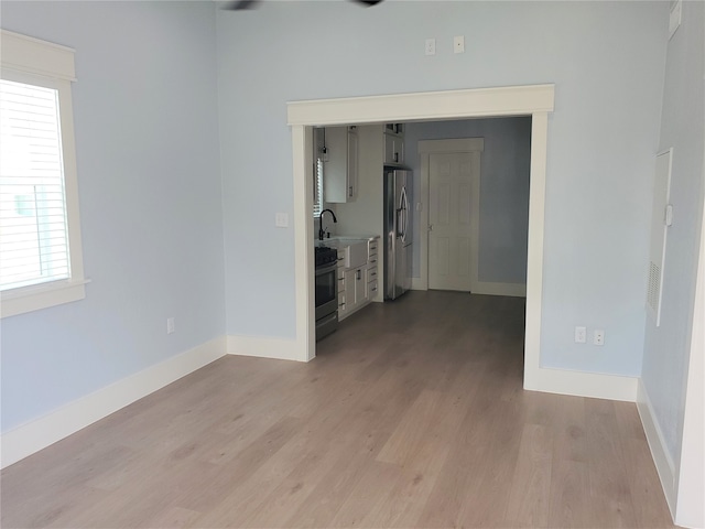 spare room featuring sink and light hardwood / wood-style floors