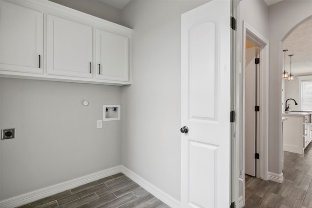 washroom with cabinets, electric dryer hookup, washer hookup, dark hardwood / wood-style flooring, and sink