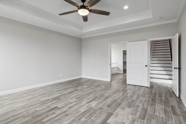 unfurnished bedroom with light hardwood / wood-style floors, ceiling fan, a raised ceiling, and ornamental molding