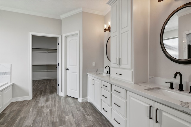 bathroom featuring wood-type flooring, a bathing tub, crown molding, and vanity