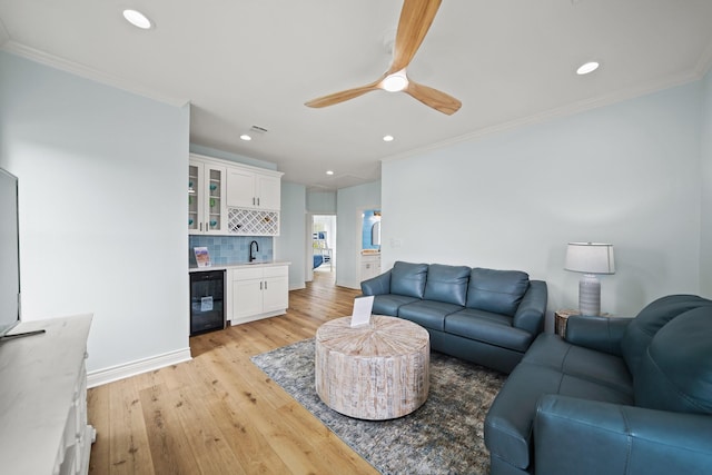 living room featuring crown molding, sink, wine cooler, and light hardwood / wood-style floors