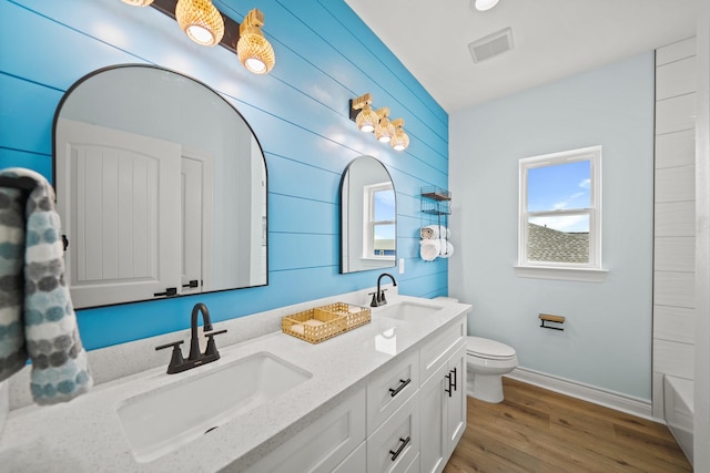 bathroom featuring vanity, toilet, hardwood / wood-style floors, and wood walls