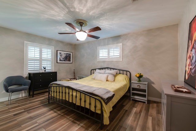 bedroom featuring dark hardwood / wood-style flooring, ceiling fan, and multiple windows