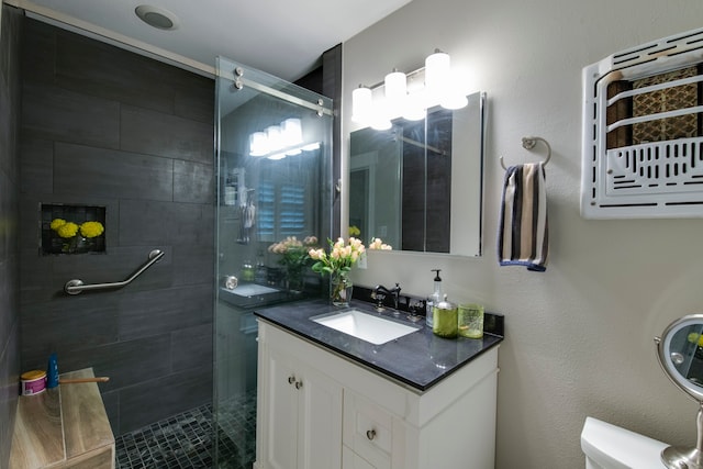 bathroom with toilet, a tile shower, and vanity