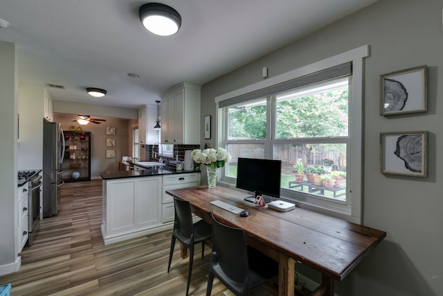 interior space featuring decorative light fixtures, hardwood / wood-style floors, appliances with stainless steel finishes, ceiling fan, and white cabinets