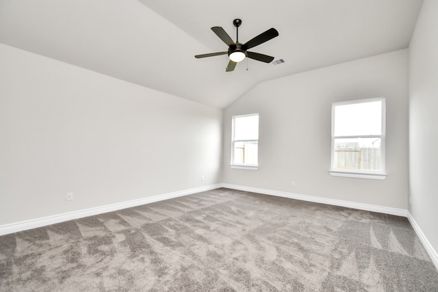 empty room featuring lofted ceiling, a wealth of natural light, ceiling fan, and carpet flooring