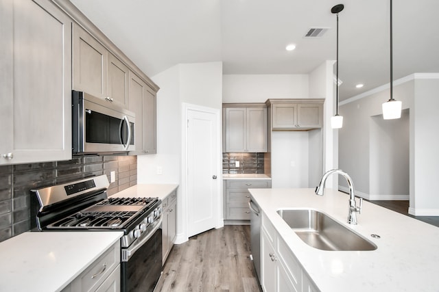 kitchen with appliances with stainless steel finishes, hanging light fixtures, decorative backsplash, and sink