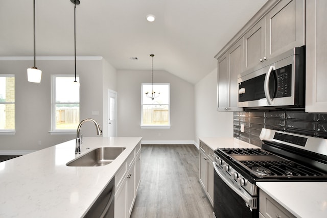 kitchen with light wood-type flooring, appliances with stainless steel finishes, decorative light fixtures, and sink