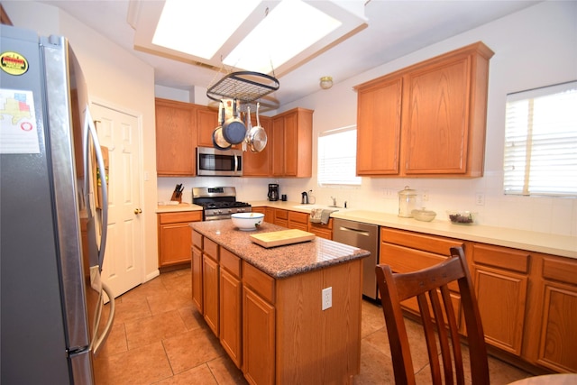 kitchen featuring a center island, light tile patterned floors, stainless steel appliances, and plenty of natural light