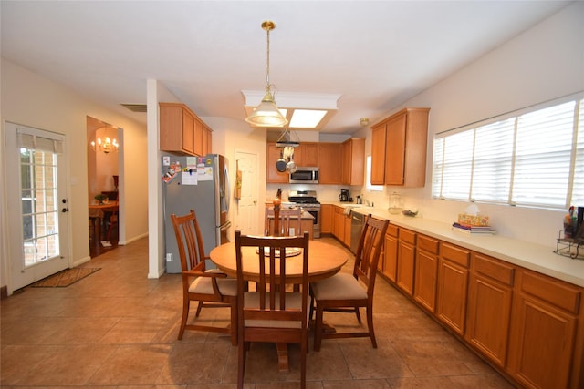 kitchen with sink, dark tile patterned floors, a notable chandelier, pendant lighting, and appliances with stainless steel finishes