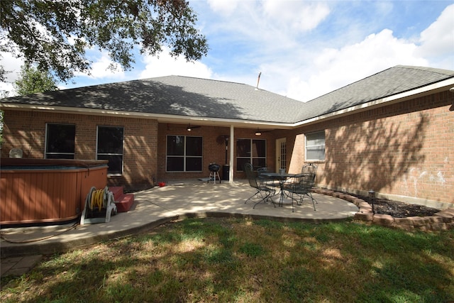 back of property featuring a lawn, a patio, and a hot tub