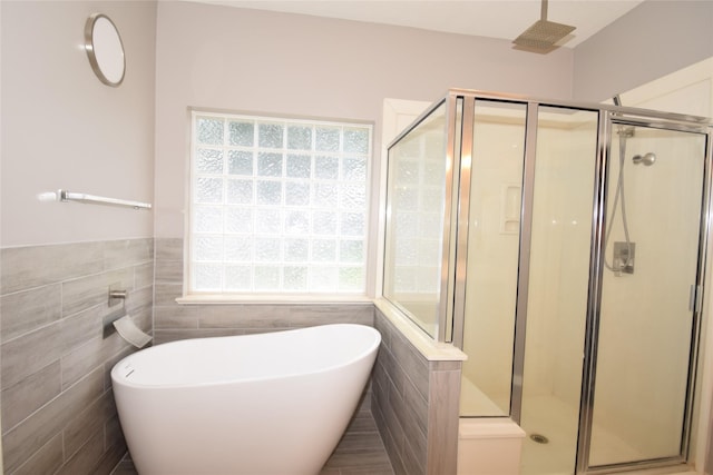 bathroom featuring plus walk in shower and tile walls