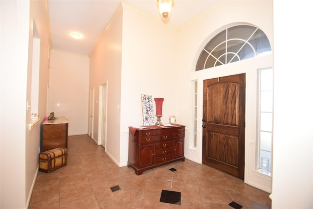 tiled entryway with a towering ceiling and crown molding