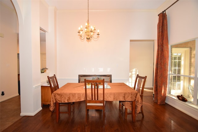 dining area with crown molding, dark wood-type flooring, and a notable chandelier