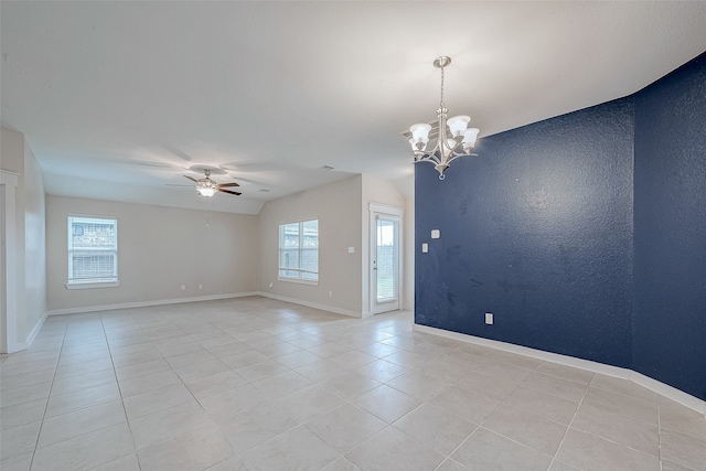 empty room featuring ceiling fan with notable chandelier, a wealth of natural light, and light tile patterned flooring