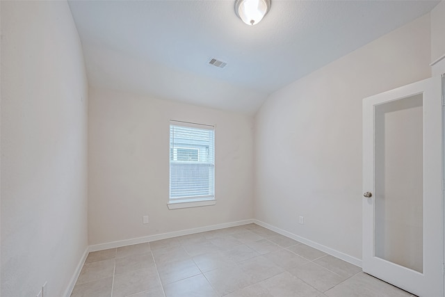 spare room featuring light tile patterned floors and vaulted ceiling