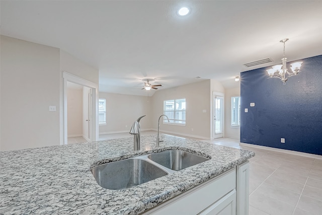 kitchen with light stone countertops, sink, light tile patterned floors, white cabinetry, and hanging light fixtures