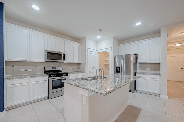 kitchen featuring backsplash, white cabinets, a center island with sink, sink, and stainless steel appliances