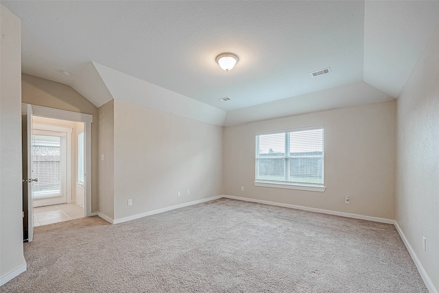 carpeted spare room with lofted ceiling