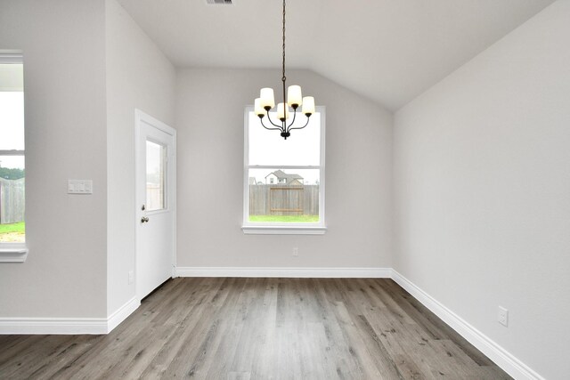 unfurnished dining area with hardwood / wood-style flooring, a chandelier, and vaulted ceiling