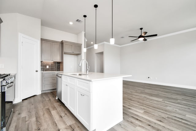 kitchen with light hardwood / wood-style flooring, sink, ceiling fan, appliances with stainless steel finishes, and a center island with sink