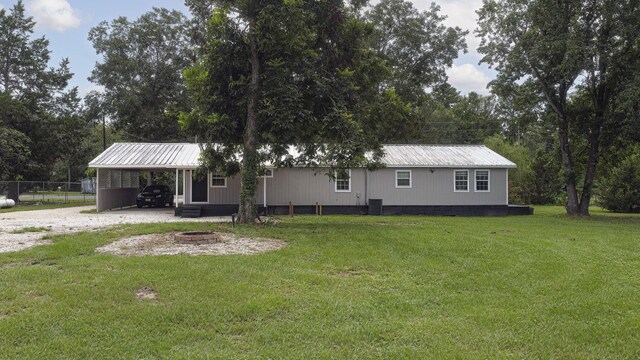 view of front of home with central air condition unit, a front yard, and a carport