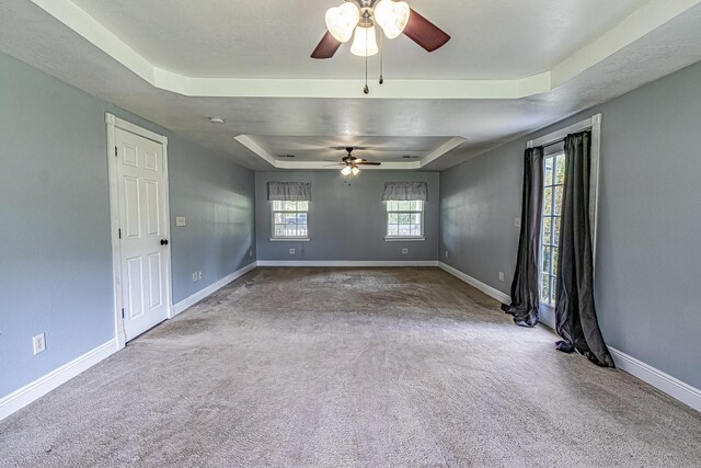 carpeted spare room with a tray ceiling and ceiling fan