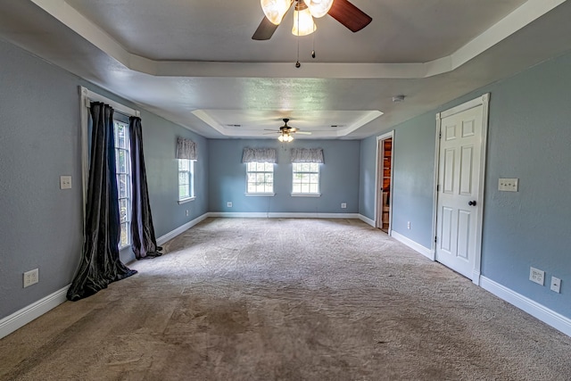 empty room featuring a tray ceiling, carpet floors, and ceiling fan