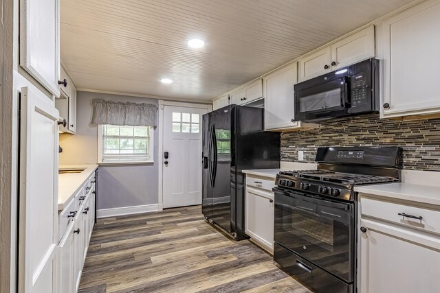 kitchen with black appliances, hardwood / wood-style floors, tasteful backsplash, and white cabinets