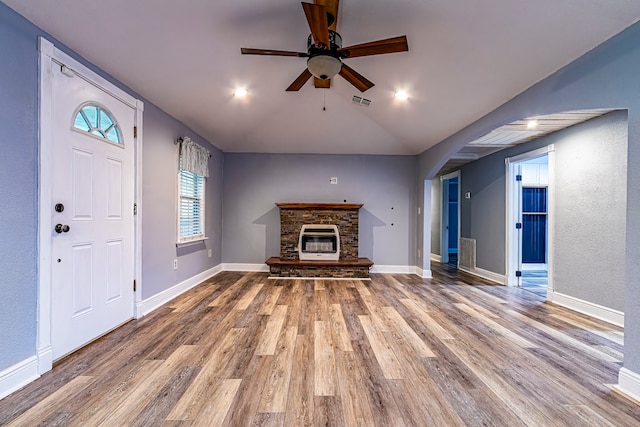 unfurnished living room featuring vaulted ceiling, hardwood / wood-style floors, ceiling fan, and a stone fireplace