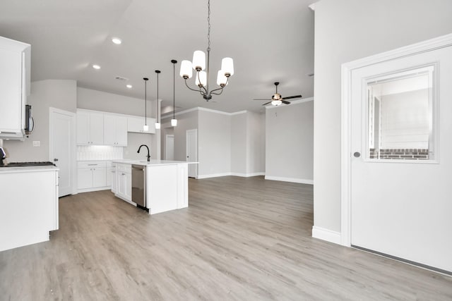 kitchen featuring light wood finished floors, appliances with stainless steel finishes, open floor plan, hanging light fixtures, and a kitchen island with sink