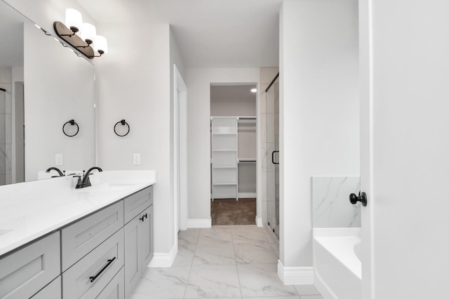 full bath with a sink, baseboards, marble finish floor, a spacious closet, and a stall shower