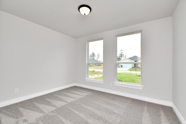 unfurnished room featuring carpet and baseboards